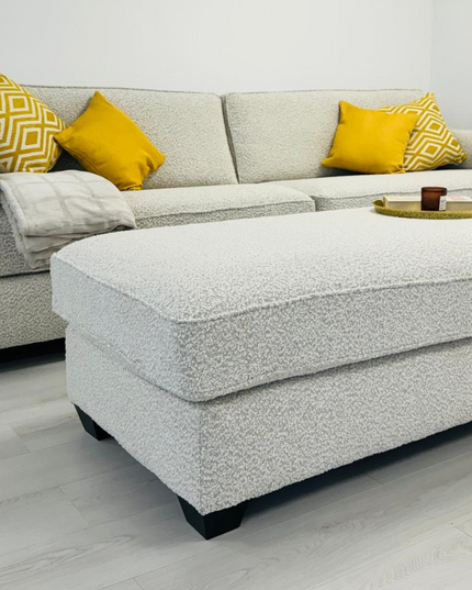 Bloomsbury luxury cream sofa with matching footstool and accent pillows in a modern living room.