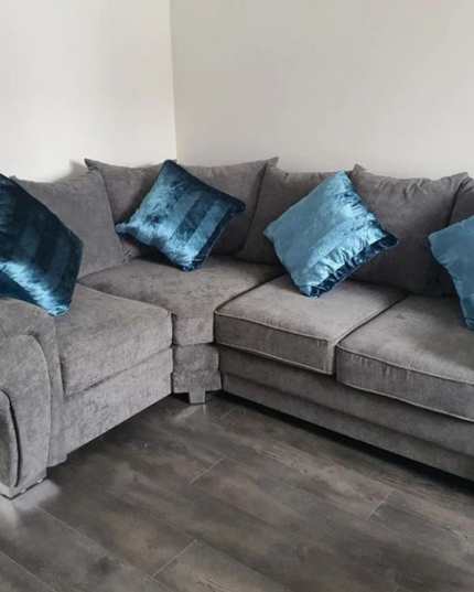 Grey corner sofa with teal accent pillows in a modern living room setting.