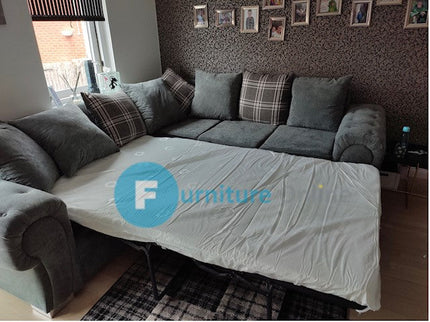 Grey sofa bed in living room with bedding extended for a cozy sleep space.